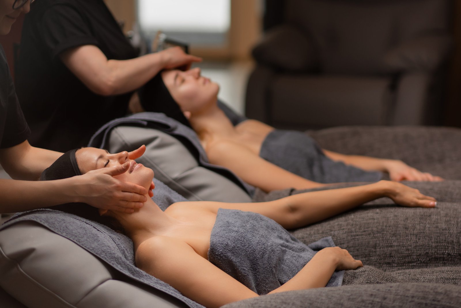 Two people enjoying relaxing facial treatments in a serene spa environment.